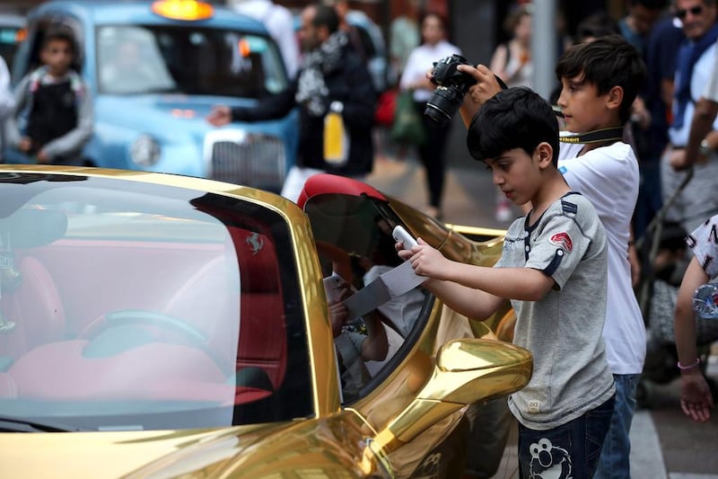 Children take photographs of a gold Ferrari in Knightsbridge. Owners of these supercars, many of whom are Qataris, Saudis, Emiratis and Kuwaitis, happily leave their luxury cars parked up on the side of the road for car enthusiasts to take photos. Dan Kitwood / Getty Images