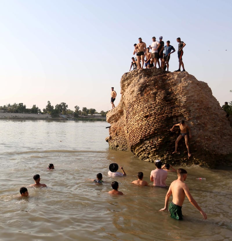 Youths swim by the ruins of an old building on the Tigris river in Baghdad, Iraq.