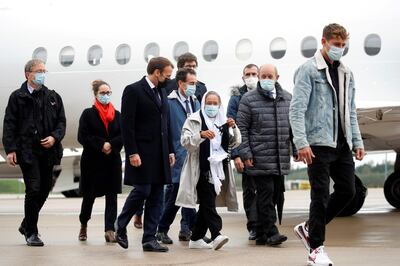 French President Emmanuel Macron (C-L) welcomes French aid worker Sophie Petronin (C) next to French European and Foreign Affairs Minister Jean-Yves Le Drian (C-R) after suspected jihadist hostage-takers freed the 75-year-old from nearly four years of captivity in Mali upon her arrival at the Villacoublay military airport near Paris on October 9, 2020. Petronin was released along with a top Malian politician and two Italian hostages late on October 8, 2020. The last French citizen known to have been held hostage anywhere in the world since her abduction in 2016, a white-robed Petronin was embraced by her son as she touched down in Mali's capital, Bamako.
 / AFP / POOL / GONZALO FUENTES
