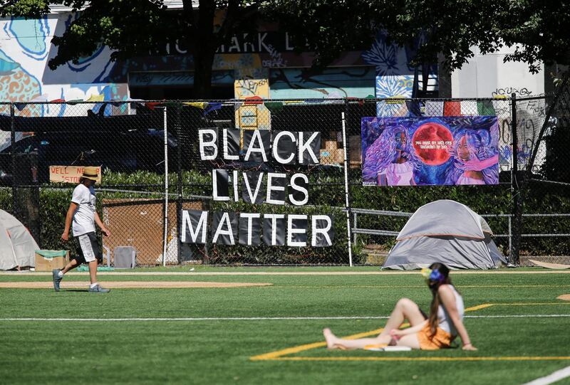 A person sits on the Cal Anderson Park field as Black Lives Matter signs hang on the fencein Seattle, Washington. Reuters