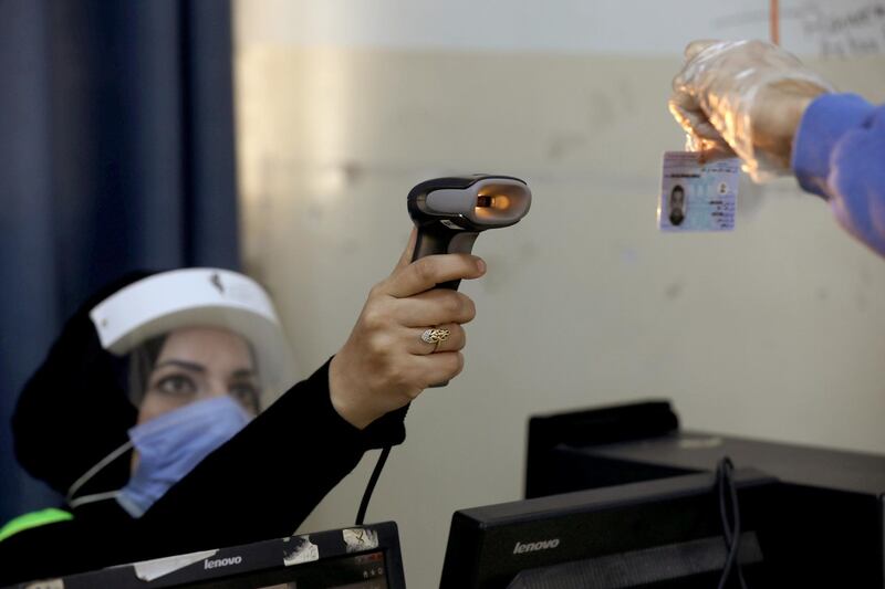 An electoral worker checks the ID card of a person during parliamentary elections. Reuters