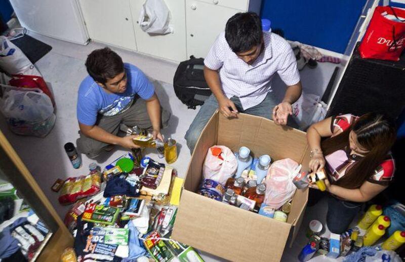 John Paul, 27, Francis, 28, and Angel Laguilles, 25, prepare a balikbayan box to send to their family in the Philippines.