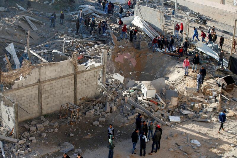 Palestinians gather around a militant target that was hit in an Israeli airstrike. Mohammed Salem / Reuters