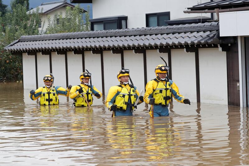 Police wade through a flooded area. REUTERS