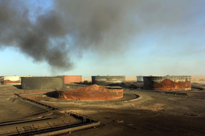 (FILES) A file photo taken on January 08, 2016 shows smoke billowing from a petroleum storage tank after a fire was extinguished at Al-Sidra oil terminal, near Ras Lanuf in the so-called "oil crescent" along Libya's northern coast.  A militia opposed to Libya's military strongman Khalifa Haftar on June 14, 2018 attacked eastern oil sites under his control, setting fire to at least one crude reservoir, a military source said. The attack was carried out by the Benghazi Defence Brigades, including fighters driven from Benghazi city by forces loyal to Haftar, the source said. / AFP / STRINGER
