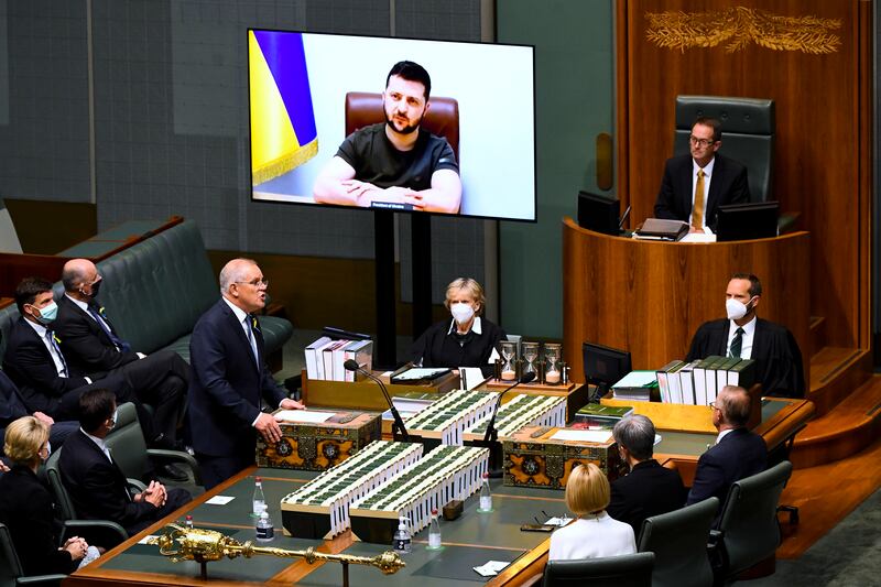 Australian Prime Minister Scott Morrison, standing, welcomes Ukrainian President Volodymyr Zelenskyy to address the House of Representatives via video link at Parliament House in Canberra.  Mr Zelenskyy appealed directly to Australian legislators for more help in the war against Russia, including armoured vehicles and tougher sanctions. AP