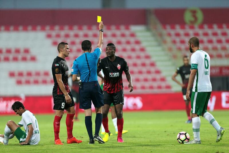 Al Ahli’s Asamoah Gyan receives a yellow card after fouling Emirates’ Haitham Ali, ground, during their Arabian Gulf League match in Dubai on Saturday. Christopher Pike / The National