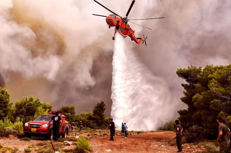 A firefighting helicopter drops water to extinguish flames during a wildfire at the village of Kineta, near Athens, on July 24, 2018. AFP