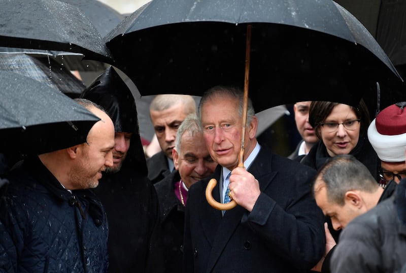 Prince Charles shelters from the rain as he walks through Manger Square in Bethlehem. EPA