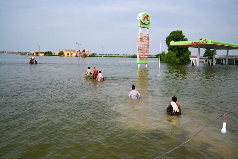 People have been left to wade through floodwaters in order to return home in Dadu District, Sindh Province. AFP