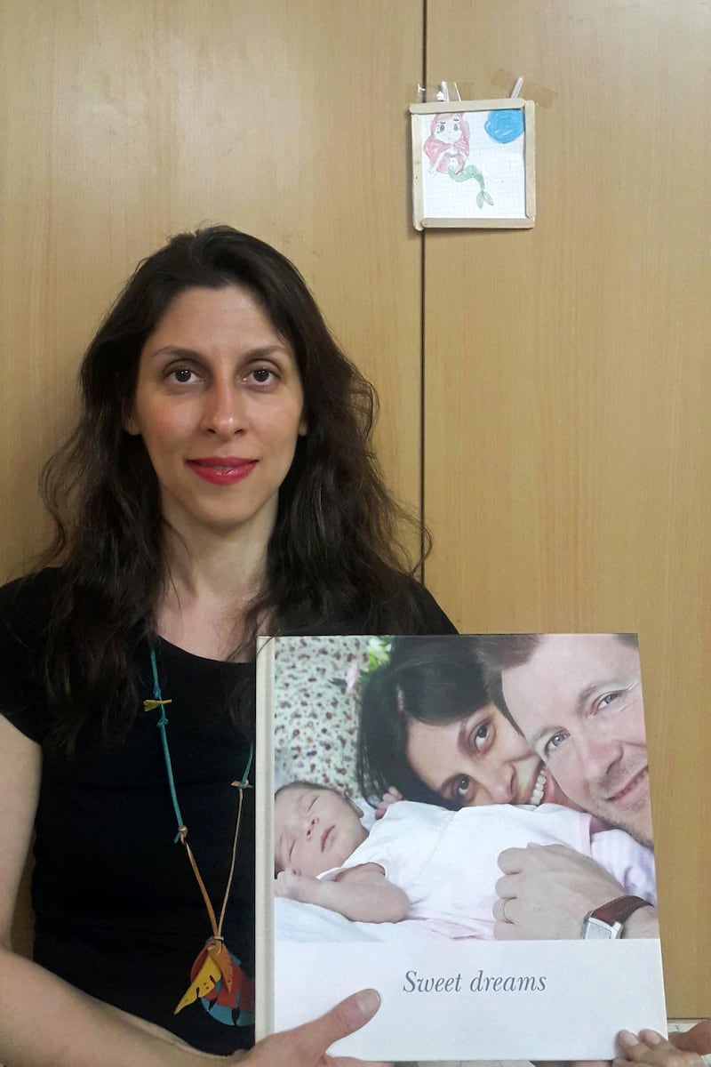 A handout picture released by the Free Nazanin campaign on March 17, 2020 shows Nazanin Zaghari-Ratcliffe holding an old picture of herself with her husband and daughter as she poses for a photograph in West Tehran, Iran following her release from prison for two weeks. - Nazanin Zaghari-Ratcliffe, a British-Iranian woman serving a five-year prison term in Tehran for sedition, was released from jail for two weeks on Tuesday, March 17, her husband said. (Photo by - / Free Nazanin campaign / AFP) / RESTRICTED TO EDITORIAL USE - MANDATORY CREDIT "AFP PHOTO / FREE NAZANIN CAMPAIGN" - NO MARKETING NO ADVERTISING CAMPAIGNS - DISTRIBUTED AS A SERVICE TO CLIENTS