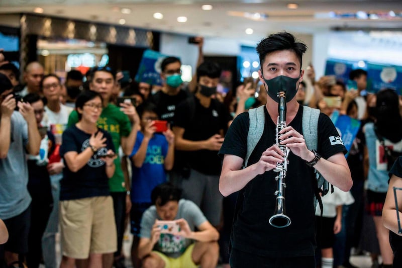 A man plays the clarinet as people sing at an anti-government rally inside a shopping mall at the Sha Tin district of Hong Kong.  AFP