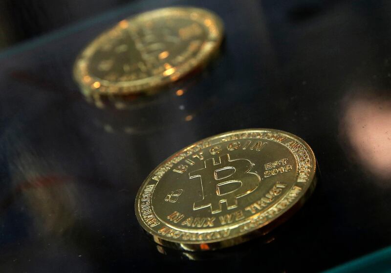 FILE- In this Dec. 8, 2017, file photo, coins are displayed next to a Bitcoin ATM in Hong Kong. The IRS says that cryptocurrency transactions are taxable by law. That means people who made money (or lost it) on Bitcoin trades, â€œminedâ€ Ethereum or even bought a cup of coffee with digital currency face potential tax implications. Failure to report it could mean potential audits, fines and penalties. (AP Photo/Kin Cheung, File)