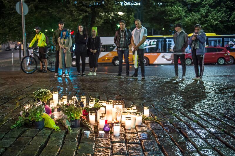 People place candles and flowers to the site where two people were stabbed to death in Turku, Finland. EPA / Markku Ojala.