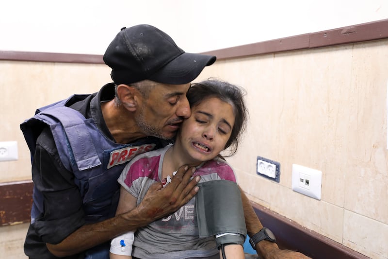 A Palestinian journalist comforts his niece after she was wounded in an Israeli strike on Nuseirat refugee camp. AP