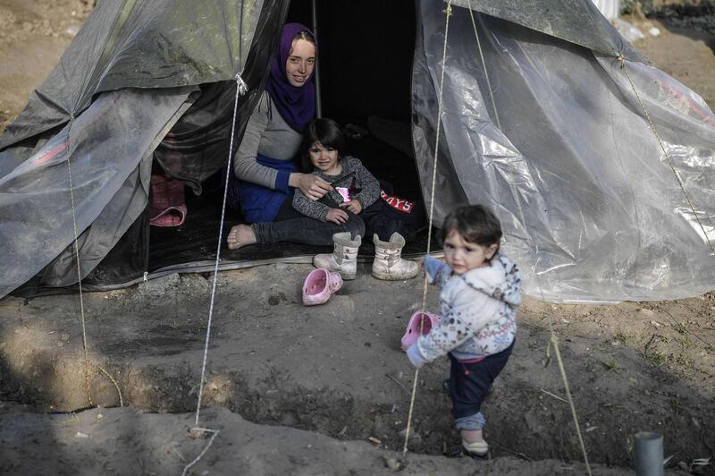 TOPSHOT - A syrian woman sits in her tent with her children in the Vial refugee camp, on the Greek island of Chios, on December 10, 2019. The Vial camp on the island of Chios has only 1,000 places, but nearly 5,000 asylum seekers currently live there in unsanitary conditions and many camps  situated in the nearby olive groove are without toilets, bathrooms, electricity and water. In addition to lack of hygiene, "insecurity, especially at night, is often mentioned by women," reports the Office of the High Commissioner for Refugees (UNHCR). In the improvised camp, single men of various nationalities live together, adolescent girls or elderly or pregnant women. The NGO Human Rights Watch recently sounded the alarm, calling on the Greek government to "act immediately to ensure safe and humane conditions for women and girls" in camps on the Greek islands. / AFP / LOUISA GOULIAMAKI
