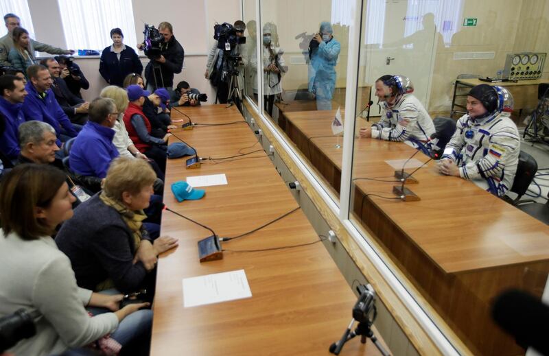 Nick Hague and Alexey Ovchinin speak with their relatives through a safety glass prior to the launch. AP Photo