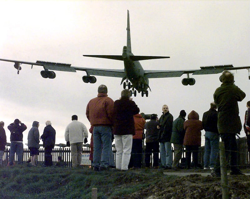 Residents watch a giant American B52 bomber arrive at the RAF Fairford air base near Cirencester, Gloucestershire,  21 February as part of the NATO military build-up over Kosovo. A group of seven of the giant aircraft, each capable of carrying 30 tons of bombs and missiles, were expected to land at the air base. (Photo by TIM OCKENDEN / PA / AFP)