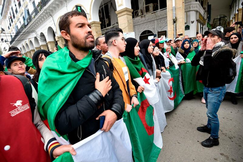 Algerian protesters hold the national flag as they take part in an anti-government rally in the centre of the capital Algiers.  AFP