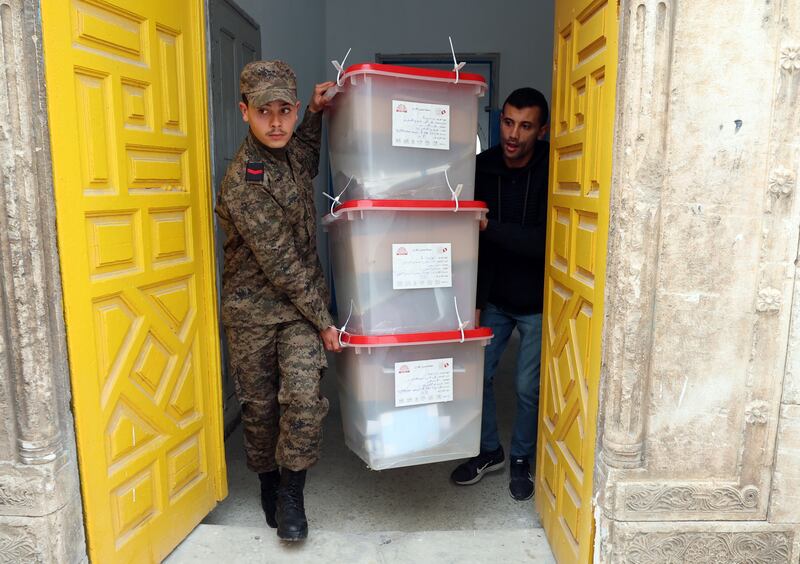 A soldier and an election worker carry ballot boxes into a polling station in Tunis. EPA 