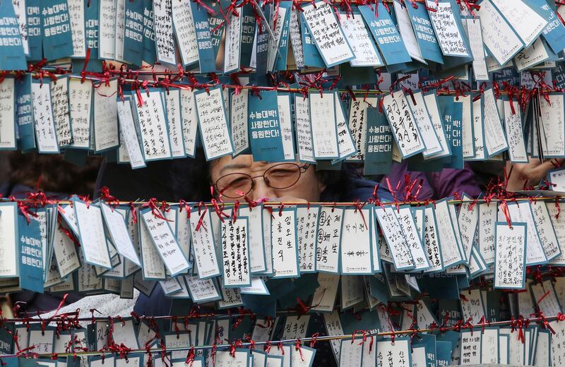 A mother ties a note to a line to wish her child good luck in an upcoming college entrance exam at Jogye Temple in Seoul, South Korea. AP Photo