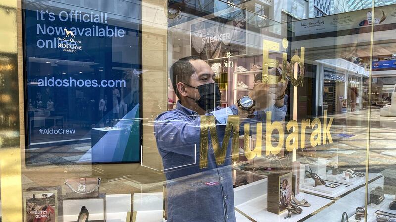 A shop attendent puts up an Eid Mubarak sticker on a shop window in the mall. Eid decorations in Festival City Mall with shoppers preparing for Eid on May 10th, 2021. 
Antonie Robertson / The National.
Reporter: Patrick Ryan for National.