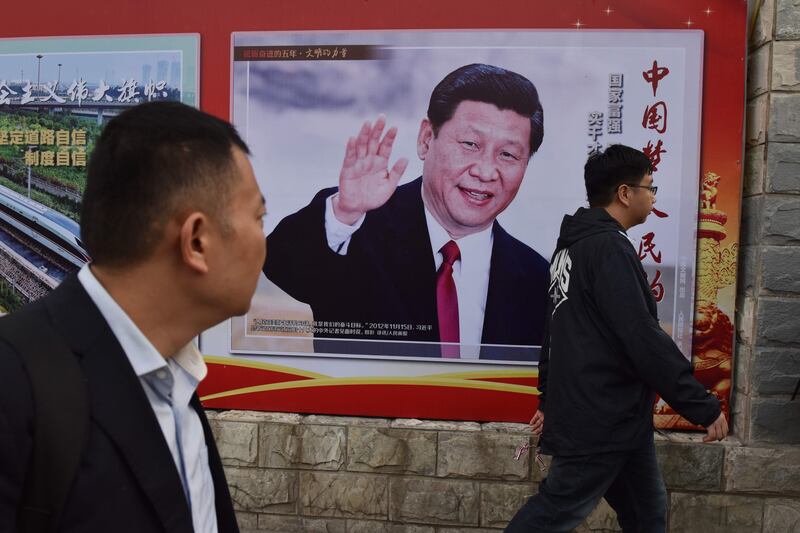 TOPSHOT - People walk past a poster featuring Chinese President Xi Jinping with a slogan reading "Chinese Dream, People's Dream" beside a road in Beijing on October 16, 2017. 
As Chinese leader Xi Jinping prepares to embark on a second five-year term this week, the impulsive leaders of North Korea and the United States could spoil his party. / AFP PHOTO / GREG BAKER