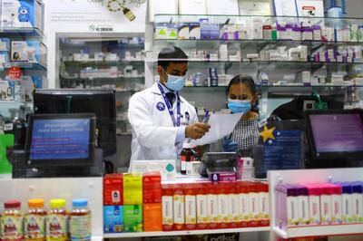 Pharmacists are seen behind a counter covered by glass, during the 24 hour lockdown to counter the coronavirus (Covid-19) outbreak in Dubai, United Arab Emirates April 6, 2020. REUTERS/Ahmed Jadallah