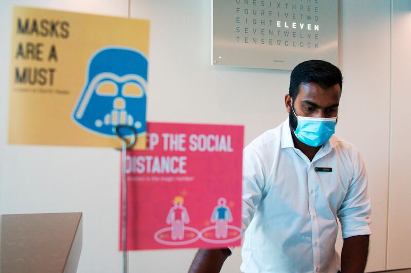 In this Monday, July 6, 2020 photograph, a front desk employee wearing a mask due to the coronavirus pandemic works on his computer at the Rove City Centre Hotel  in Dubai, United Arab Emirates, Monday, July 6, 2020. Dubai reopened for tourists Tuesday amid the coronavirus pandemic, hoping to reinvigorate a vital industry for this city-state before its crucial winter tourist season. (AP Photo/Jon Gambrell)