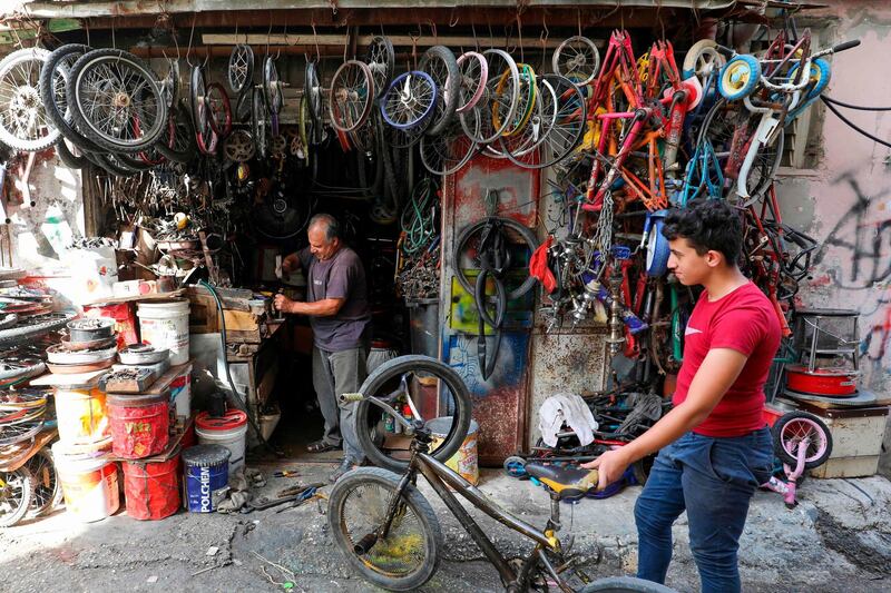 A Palestinian boy waits on a bicycle repair man outside his store in the Amari refugee camp near the West Bank city of Ramallah. AFP