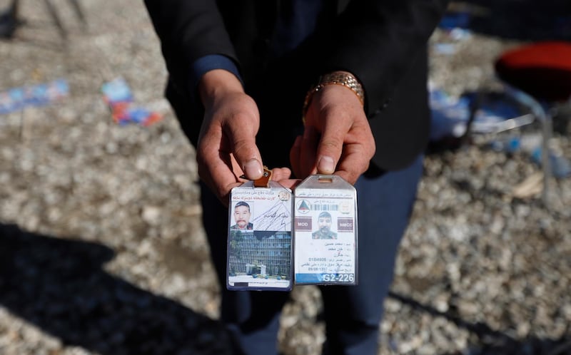 An Afghan man shows identity cards found at the scene of an attack the day before, in Kabul, Afghanistan.  EPA