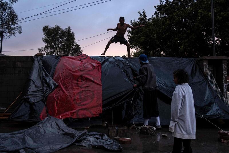 Migrants improvise a tent outside the temporary shelter after heavy rain. AFP