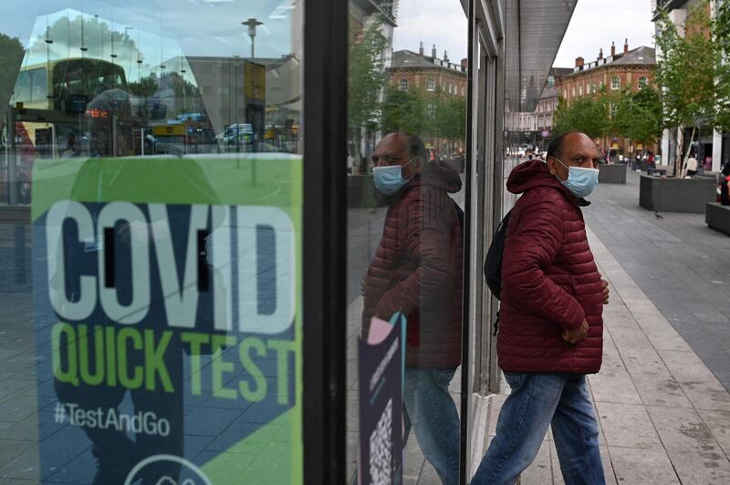 A man wearing a face covering passes a Covid-19 information sign as he exits the Bus Station in Blackburn, north-west England. AFP