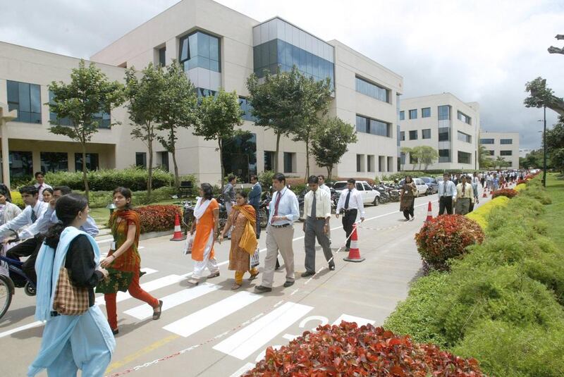 Infosys employees walk in its campus in Bangalore. Many Indians are looking abroad for more work opportunities and better wages. Gautam Singh / AP Photo