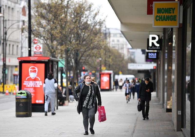 A pedestrian wearing a face covering due to Covid-19, walks past closed shops on a quiet Oxford Street in central London on March 24, 2021. Britain's annual inflation rate unexpectedly fell in February as coronavirus curbs sparked heavy discounting for clothing and footwear, official data showed Wednesday, soothing market concerns over inflationary pressures. / AFP / JUSTIN TALLIS
