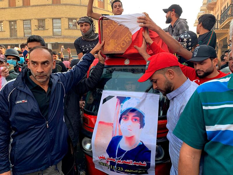 Mourners and protesters escort the flag-draped coffin of Munir Ali, seen in poster, whose family said was killed during anti-government demonstrations, during his funeral in Baghdad. AP Photo