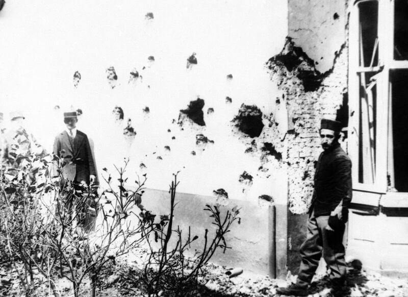 A man stands next to a building damaged by shrapnel from bombs dropped from a Zeppelin in Antwerp, Belgium.