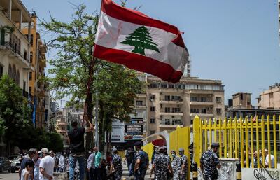 epa08431539 Anti-government protesters carry placards with Arabic words reading 'calling for the imprisonment of energy ministers', next to Lebanese policemen during a protest in front of the Ministry of Justice in Beirut, Lebanon, 19 May 2020. In addition to increasing hours of rationing electricity, the country is currently going through the worst financial crisis in history as the Lebanese Lira has slumped since October, hiking prices, fueling unrest and locking depositors out of their US dollar savings.  EPA/NABIL MOUNZER