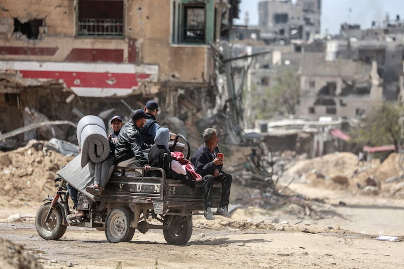 Palestinians move with their belongings on a road lined with destroyed buildings, in Khan Younis, in the south of the Gaza Strip, on April 22. AFP