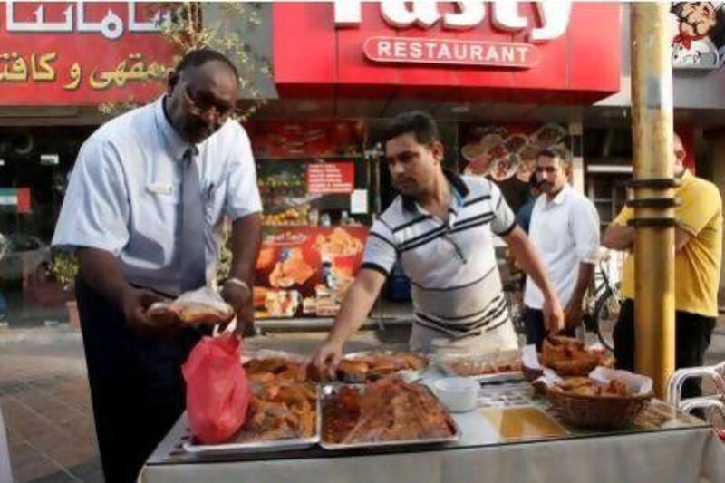 Abdelrahim Osman Gader inspects fried foods displayed outside a restaurant in Deira.
