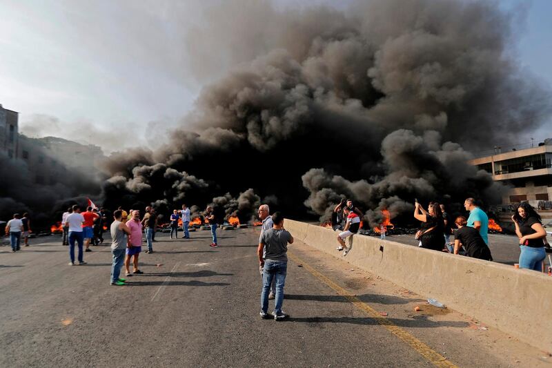 Lebanese demonstrators gather on a highway blocked by burning tyres in Nahr Ibrahim north of Beirut. AFP