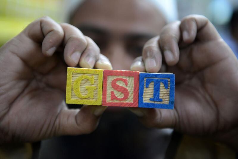 An Indian consumer goods trader shows letters GST representing Goods and Services Tax (GST) at his shop in Hyderabad. AFP