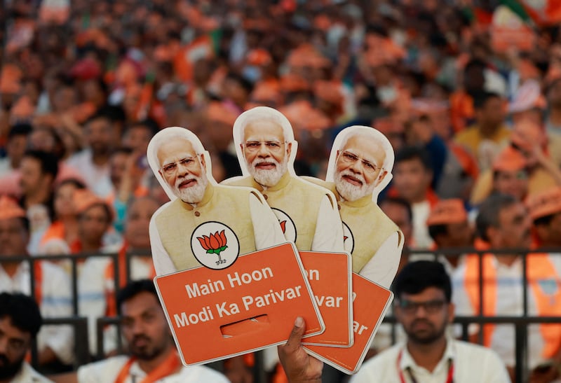 A supporter of India's ruling Bharatiya Janata Party (BJP) holds cutouts of Prime Minister Narendra Modi during an election campaign where Modi speaks, in Bengaluru. Reuters