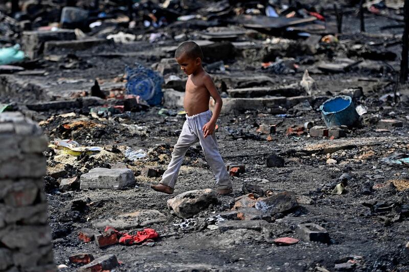 TOPSHOT - A young Rohingya refugee looks for his belongings amid the charred remains of his camp following a fire incident that broke out earlier today in New Delhi on June 13, 2021.  
 / AFP / Money SHARMA
