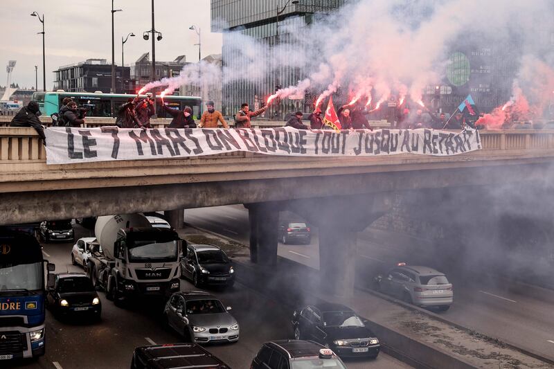 Bus drivers burn flares on a bridge above Paris's ring road amid protests against the French government's proposed pension reform. AFP