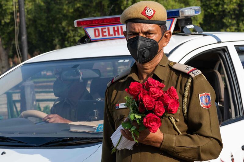 A policeman holds a bunch of roses to distribute to people in a bid to inspire them to stay home. AFP