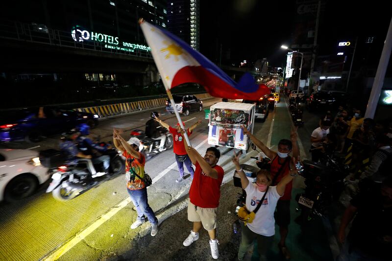 Supporters of presidential candidate Ferdinand 'Bongbong' Marcos Junior cheer outside his campaign headquarters in Mandaluyong City, Manila.  Mr Marcos Jr was leading by landslide, with most of the votes counted. EPA