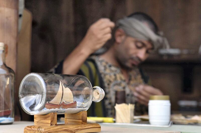 Badr Hashem, Saudi Arabia: An artist is shown with his completed craft of fashioning the almost impossible task of building a tiny ship inside a clear glass bottle in the Okaz Souq near the Saudi city of Ta’if, where a large, diverse group of artists display their crafts.