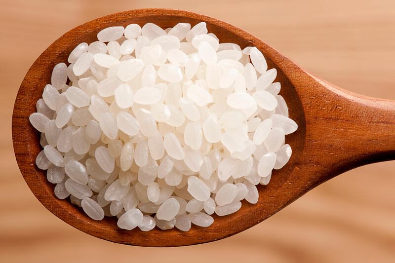 Closeup of a short-grain arborio rice portion on a wooden spoon. Getty Images