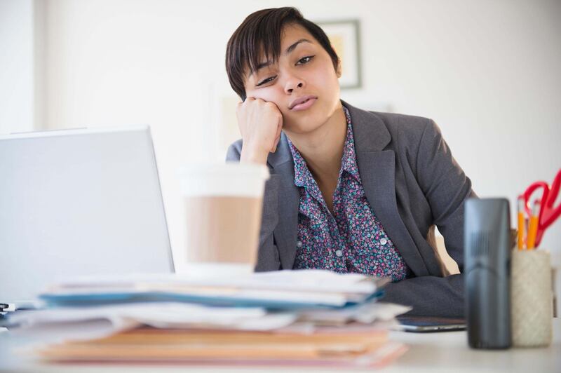 E8TB4T Bored mixed race businesswoman sitting at office desk. Alamy